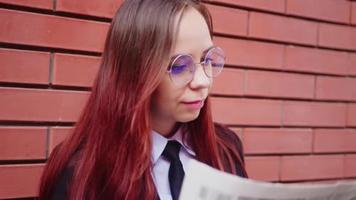 Junge Frau liest Zeitung auf der Straße