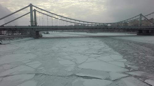 Una superficie congelada del río y un puente sobre ella en medio de un paisaje urbano invernal