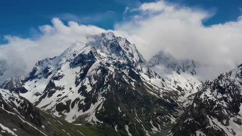 Air Flight Through Mountain Clouds Over Beautiful Snowcapped Peaks of Mountains and Glaciers
