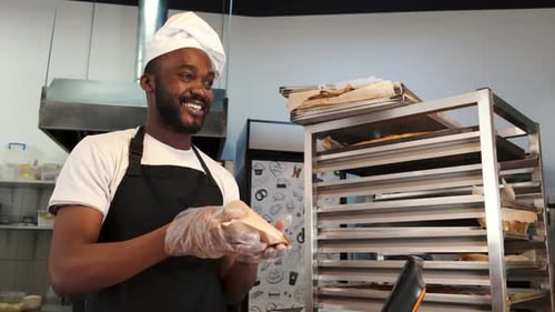 Smiling Baker Hands Pastry to Customer in Bakery