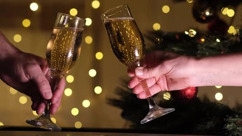 Feliz Ano Novo e Natal tilintando taças de champanhe no fundo da árvore de Natal e bokeh