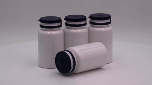 White Supplement Bottles with Blue Lids on White Surface