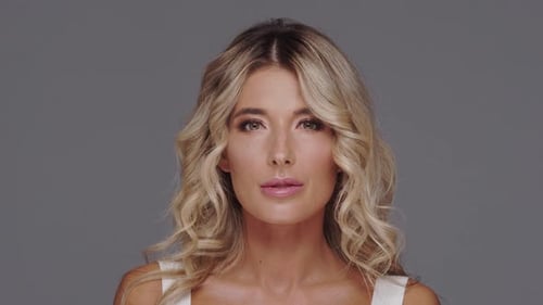 Studio portrait of young and beautiful blond woman over grey background.