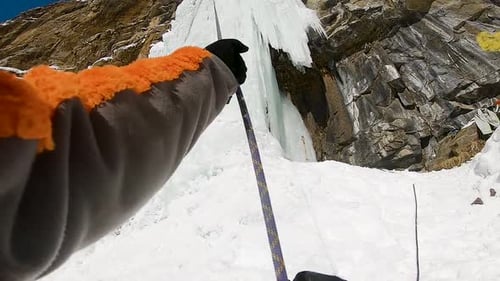 Mann klettert Eiswasserfall mit Seil und Eisgerät
