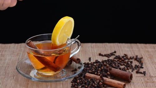 man puts cinnamon sticks in a cup of hot tea