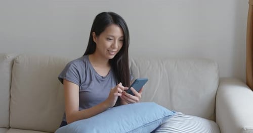 Woman Using Mobile Phone While Relaxing on Sofa