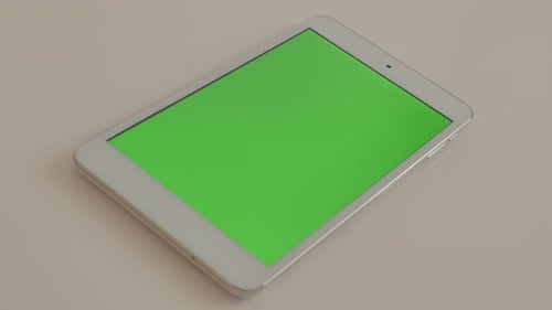 Tablet PC with green screen display on white reflective background 4K 2160p UltraHD footage - Greens