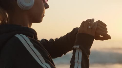 Woman Checks Smartwatch at Beach Sunset