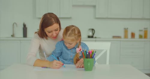 Woman and Child Drawing Together at Kitchen Table