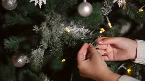 Decorating Christmas Tree With Ornaments and String Lights