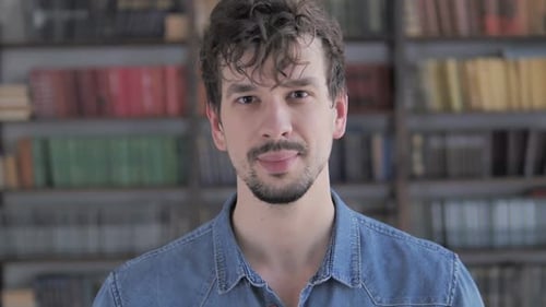 Smiling Young Adult in Front of Bookshelf