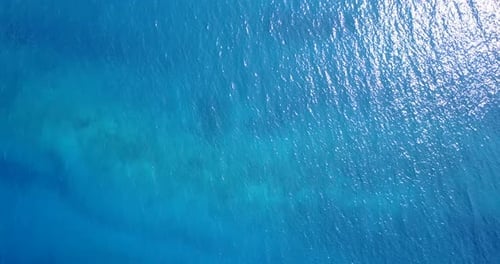 Daytime overhead clean view of a white sandy paradise beach and blue water background in colourful 4