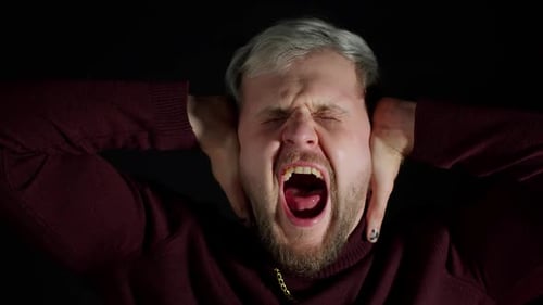 Man Screaming with Frustration Against a Black Backdrop