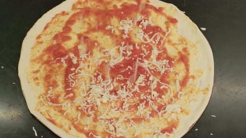 Close Up of Chef is Spreading Tomato Sauce on Pizza Dough with a Metal Ladle in Traditional Italian
