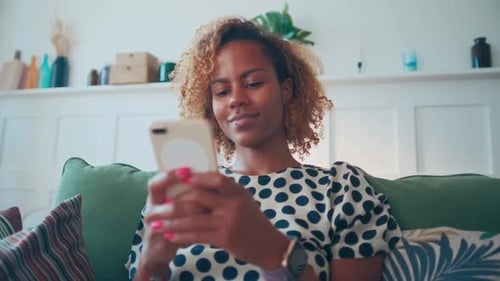 Young Woman Using Smartphone on Couch Indoors