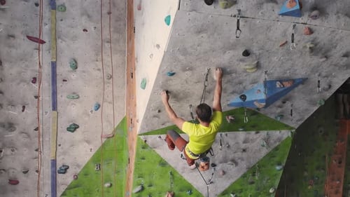 Young Woman Rock Climber is Climbing At Inside Climbing Gym