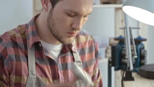 Man Using Hammer and Tool in Workshop
