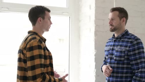 Two Men Talking Indoors, Wearing Plaid Shirts
