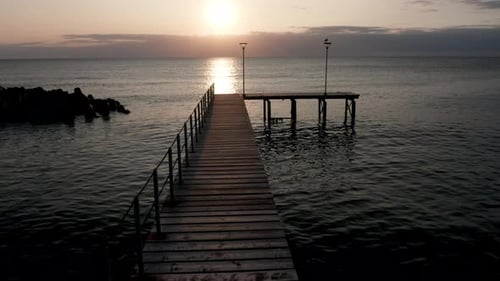 Video mit aufgehender Sonne und Holzbrücke an der Meeresküste