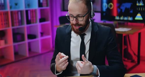Manager in Glasses Wears Headset During Video Conference on Computer in Evening Office