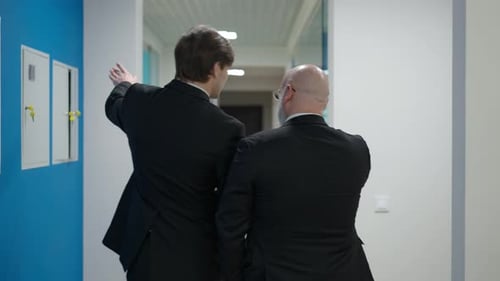 Live Camera Follows Two Confident Elegant Men Walking in Office Corridor Discussing Business