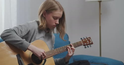 Teen Plays Guitar in Living Room