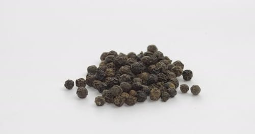 Heap of Dried Black Peppercorns on White Surface