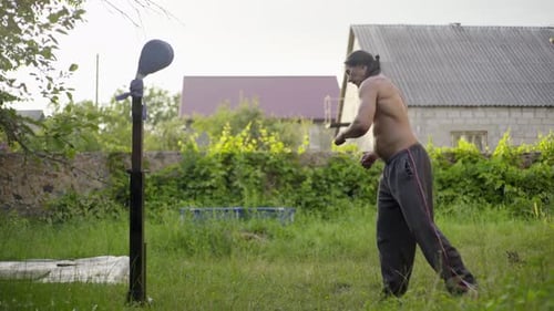 Man with Long Black Hair and a Beautiful Torso Practic Martial Arts in the Garden Practicing Kicks