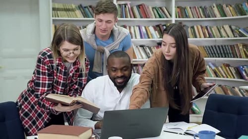 Modern Smart Multiracial Youth which Studying in University Library Using Information on Laptop