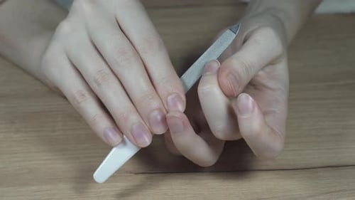 Hands filing fingernails with a metal nail file