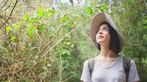 Young Caucasian woman traveling and walk in the forest with smile during summer holiday vacation.