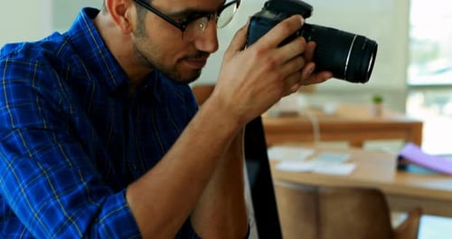 Man Inspecting Camera in Bright Modern Office