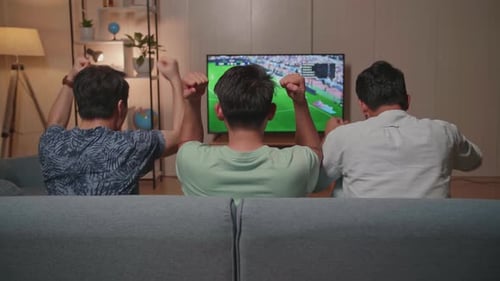 Three Friends Cheer while Watching Soccer Game at Home