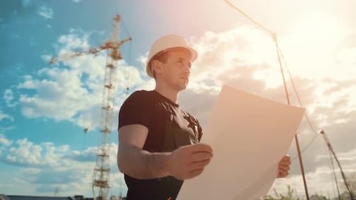 Male Construction Worker With Blueprint At Construction Site