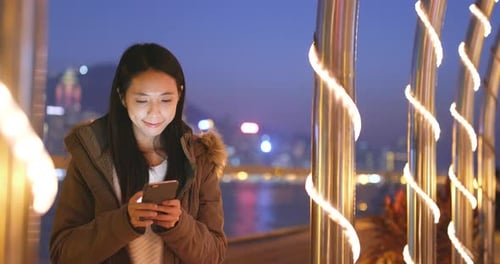 Utilisation d'un téléphone intelligent par une femme dans la ville la nuit, paysage urbain de Hong Kong
