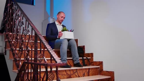 Empresario desesperado siendo despedido sentado en las escaleras