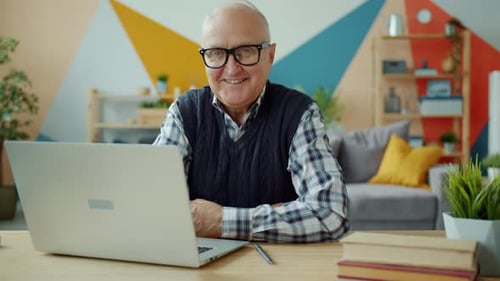 Senior Man Smiling with Laptop at Home