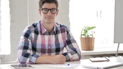 Young Man in Office Looking at Camera