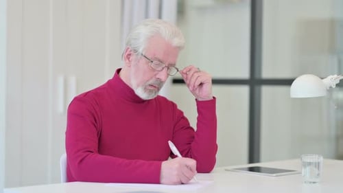 Alter Mann schreibt auf Papier und denkt
