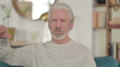 Senior Man Giving Thumbs Down Gesture Indoors