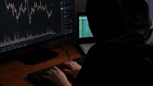 Person Typing on Keyboard in Front of Monitors