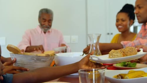 Side view of multi generation black family having food at dining table in a comfortable home 4k