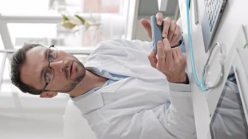Male Doctor Uses Phone, Puts On Stethoscope