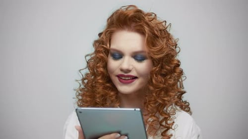 Woman Using Digital Tablet in Studio. Girl Reading Good News on Tablet Screen