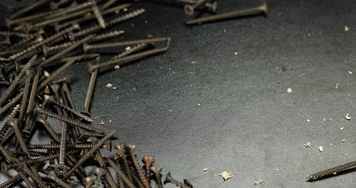 Hand Brushing Screws on a Dark Surface