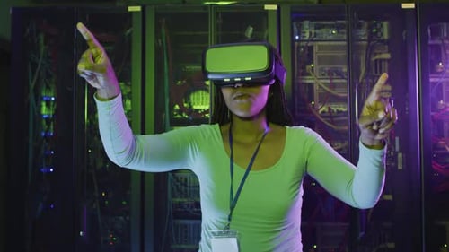 African american female computer technician using vr headset working in business server room