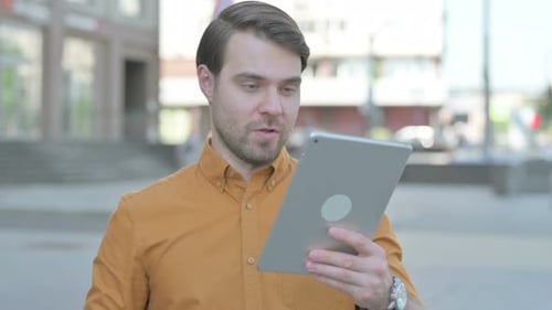 Young Man Celebrating Online Win on Tablet Outdoor