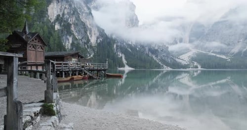 Pequeño cobertizo para botes con muelle de madera y barcos en el lago Braies con clima nublado