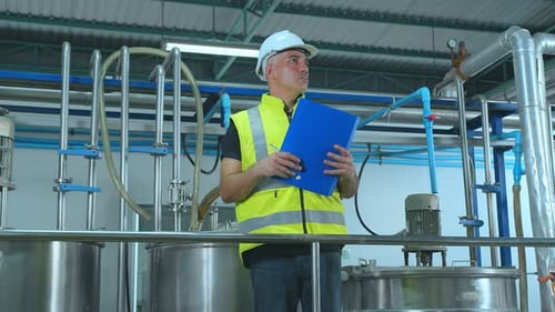 Engineer Inspecting Tanks in a Modern Factory
