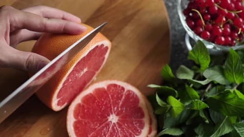 Person Slices Juicy Grapefruit with Sharp Knife